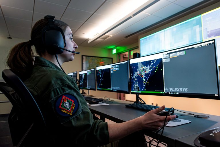 individual wearing a headset and looking at multiple computer monitors