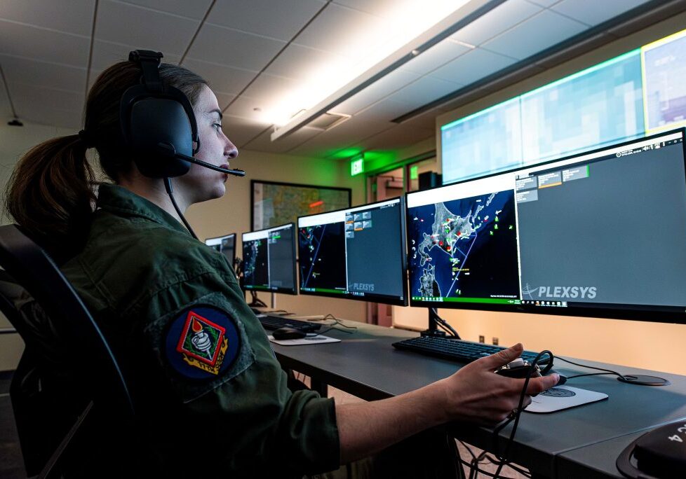 individual wearing a headset and looking at multiple computer monitors